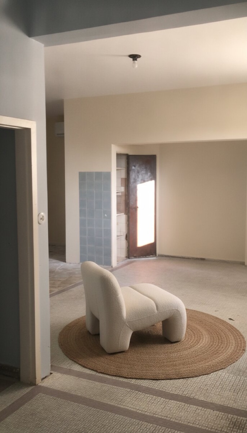 Same room with wallpaper stripped, walls repainted cream, floor tile and column kept exposed