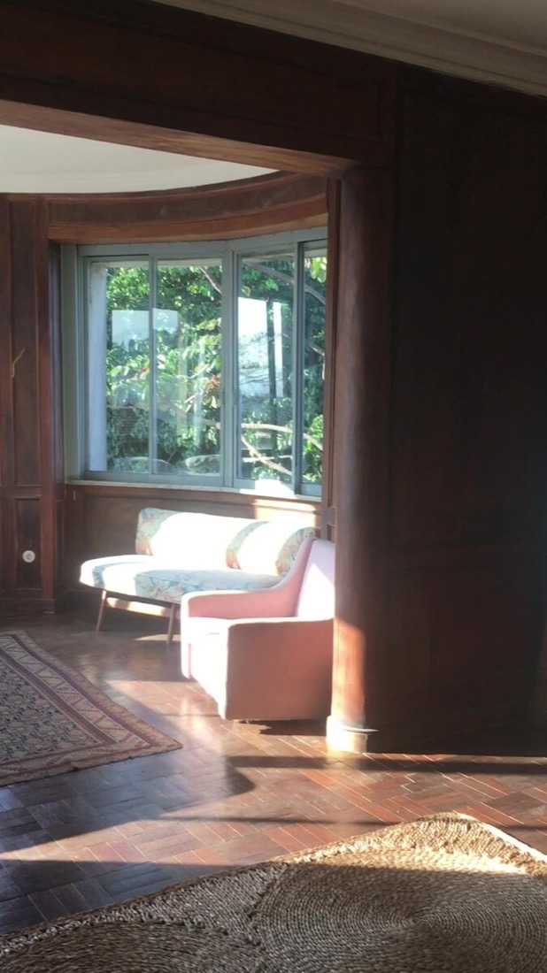 Curved wood-paneled bay window room with vintage sofa suite