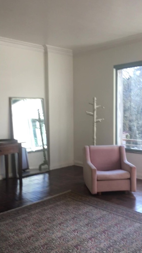 Pink armchair, floor mirror and coat rack in the same room