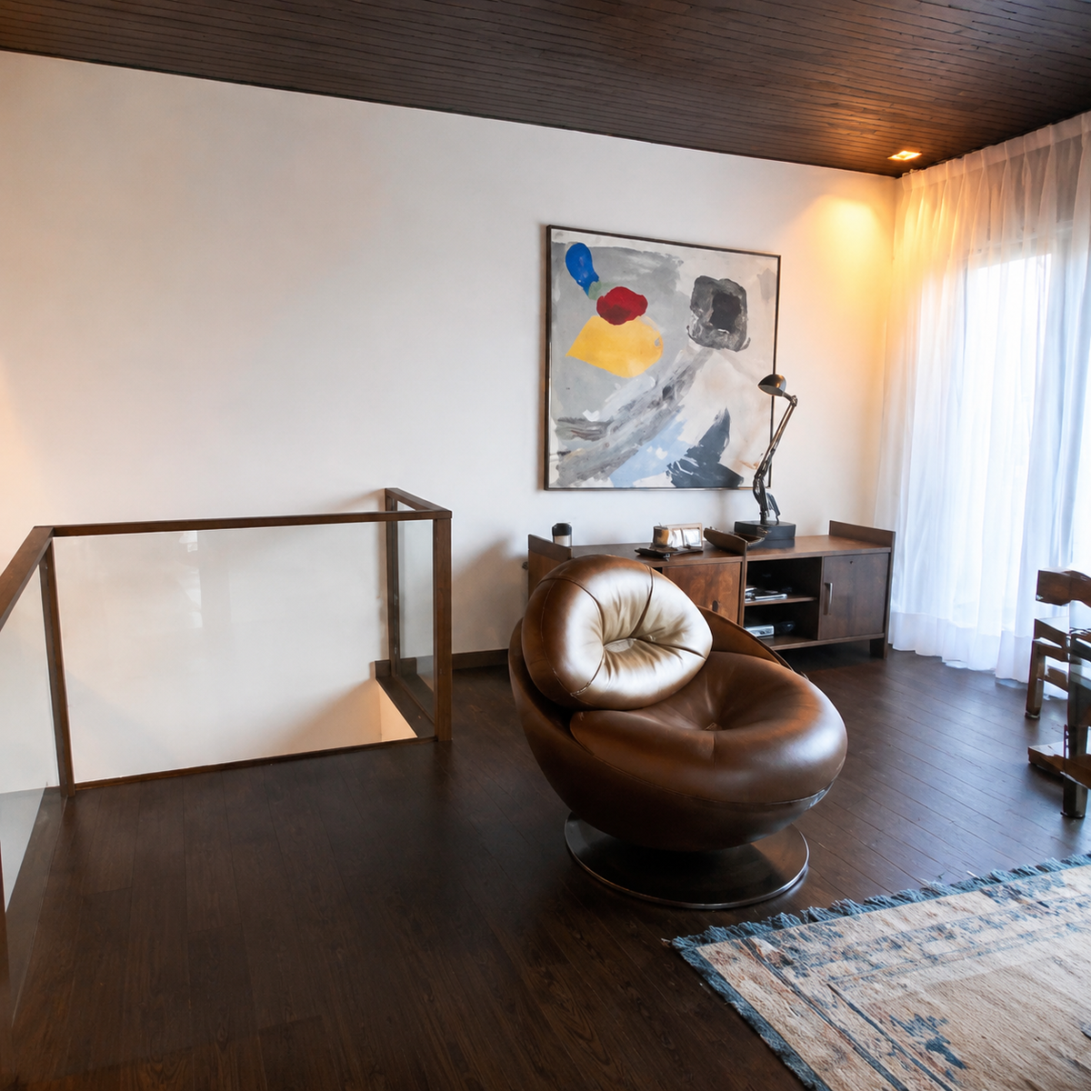 Living area with sculptural egg-shaped leather chair, staircase void