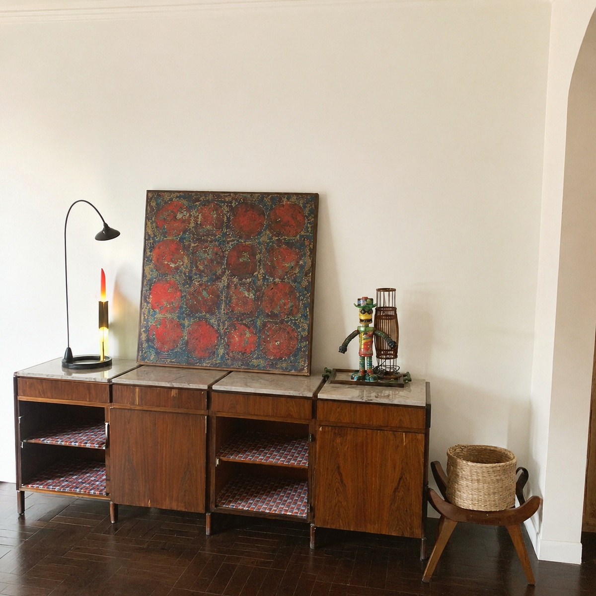 Sideboard wall with abstract painting, folk-art figures, and wicker basket