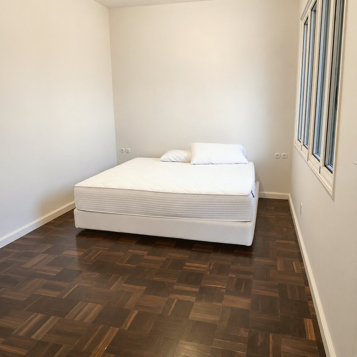 Bedroom with bare mattress on a low frame, no bedding or other furniture