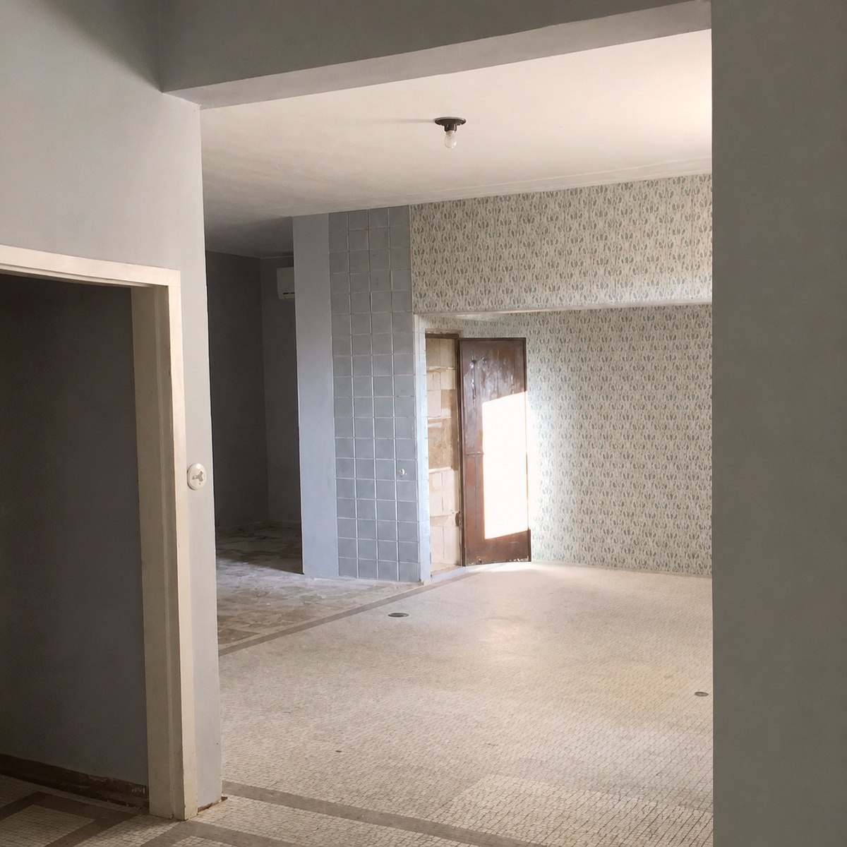 Decorative tiled column beside a patterned wallpaper wall