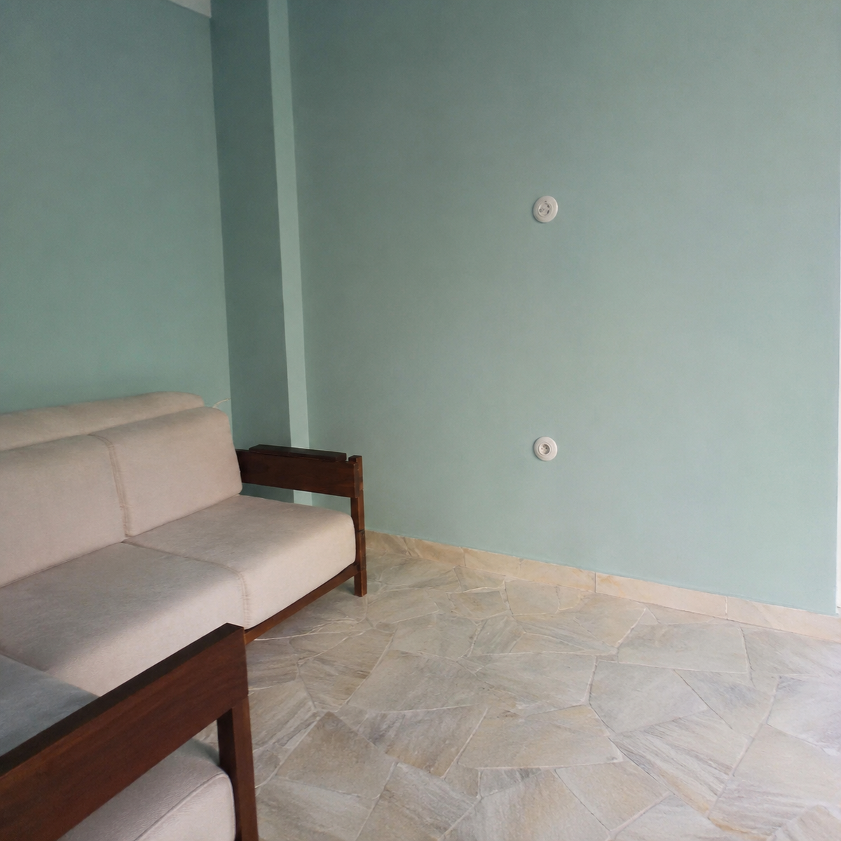 Mint-green corner with the existing sofa, no window furnishing yet