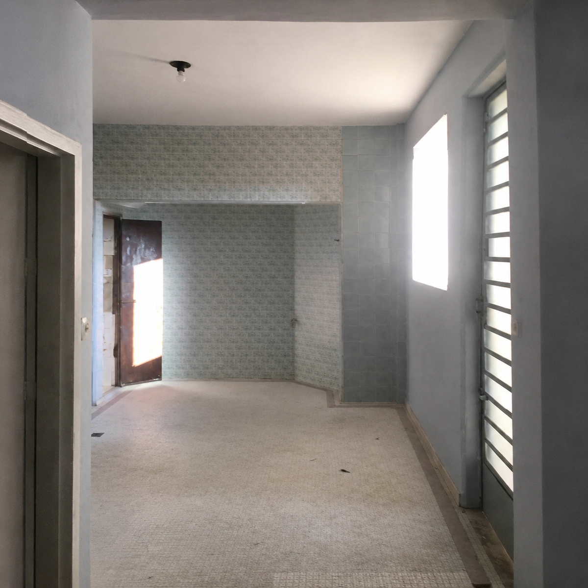 Wide view of the open-plan main room, original patterned floor tile and decorative tiled column, no furniture